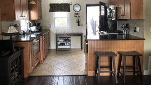 Een keuken met houten kastjes, een centraal eiland, een plafondventilator, een klok en een raam.