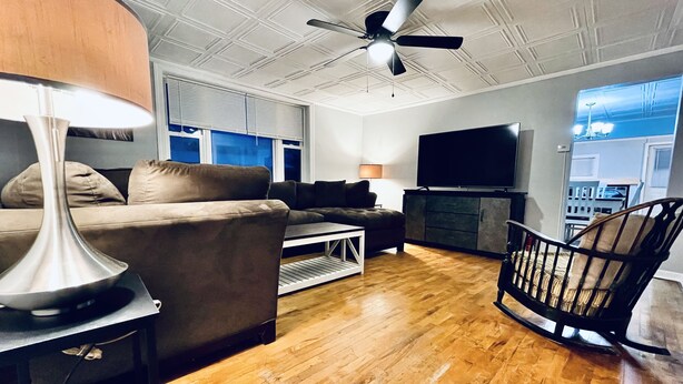 Ein Wohnzimmer mit einer Couch, einem Couchtisch, einer Lampe, einem Fernseher, einem Kamin und einem Deckenventilator.