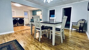 Ein Essbereich mit Tisch und Stühlen, einer Chandelüster und einem Waschraum im Hintergrund.