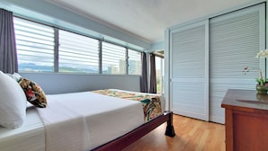 A bedroom with a bed, a view through the window, and a sliding door.