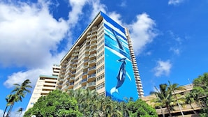 A tall hotel with multiple balconies and a large mural of a whale on the side.