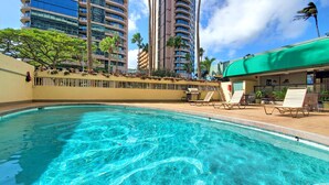 A swimming pool with lounge chairs and a restaurant with a green awning.