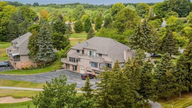 Une grande maison à deux étages avec une allée et une voiture garée devant.