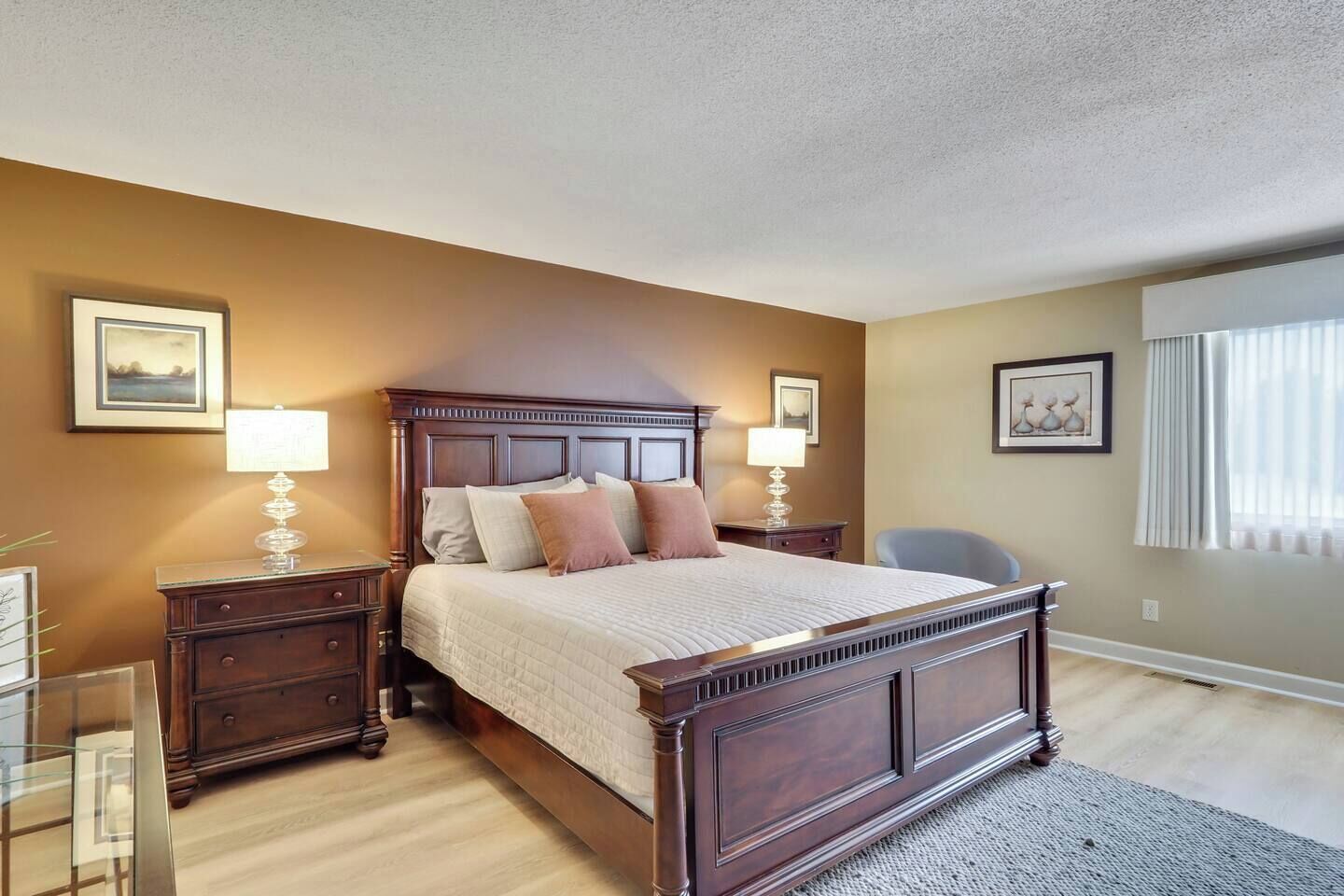 A bedroom with a large bed, nightstands, a chair, and two lamps.