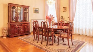 A dining room with a wooden table, six chairs, a large wooden cabinet, and a chandelier.