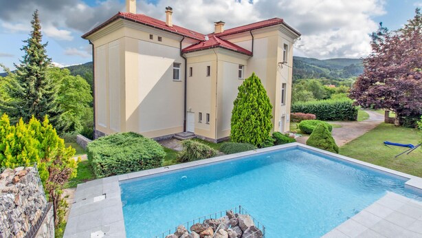 A large, two-story house with a swimming pool in the foreground.