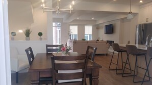 A modern kitchen with a dining area, featuring a wooden table, chairs, and a chandelier.