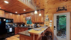A wooden cabin kitchen with a central island, wooden cabinets, a microwave, and a refrigerator.