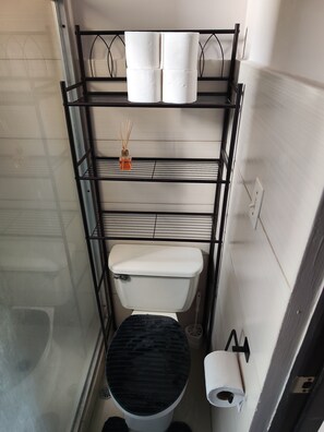 A compact bathroom with a black toilet, a white sink, and a shelf with toiletries. - Apartamento Completo para 4 huéspedes (Panama City)