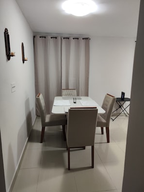 A dining area with a table and four chairs, a small side table, and a ceiling light.