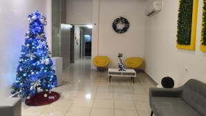 Uma sala de estar moderna com uma árvore de Natal azul, um sofá cinza, uma poltrona amarela e uma mesa de centro branca.