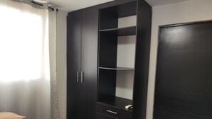 Um quarto com uma cama, um guarda-roupa e uma porta.