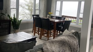 Un salon moderne avec un canapé, une table à manger et des chaises, ainsi que de grandes fenêtres.