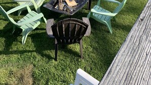 Une terrasse avec coin salon extérieur, un foyer et vue sur un lac.