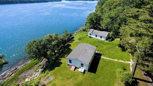 Une maison avec un grand jardin et vue sur un lac.