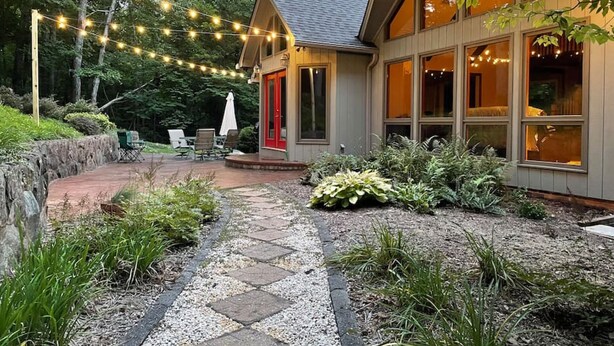 A house with a stone pathway leading to a patio area, surrounded by greenery and string lights. - Privacy, Fresh Mountain Air, and Thoughtful Hospitality (Stuart)