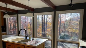 A kitchen with a large island, wooden cabinets, and a view of autumn trees through large windows. - Privacy, Fresh Mountain Air, and Thoughtful Hospitality (Stuart)