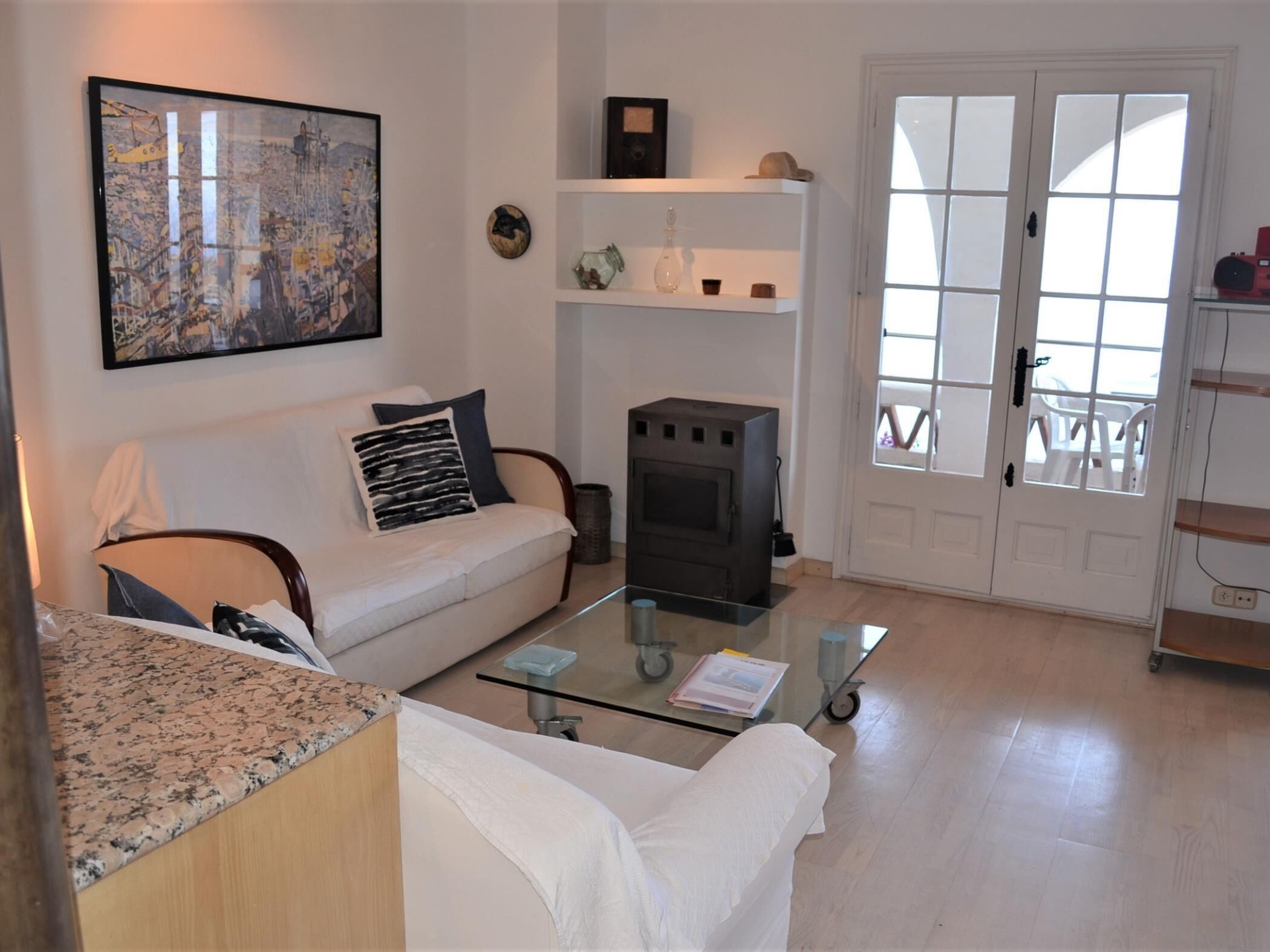 Una sala de estar con sofá, una mesa de centro de vidrio, chimenea y una puerta que da a un espacio exterior.