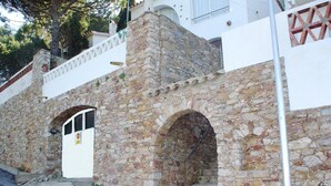 A stone building with a white door and two arched windows. - Apartament Bloc Goya (Begur)