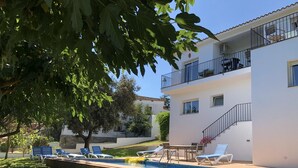 A two-story building with a swimming pool, outdoor seating, and a tree providing shade. - Villa Rosa Casa Begur (Begur)