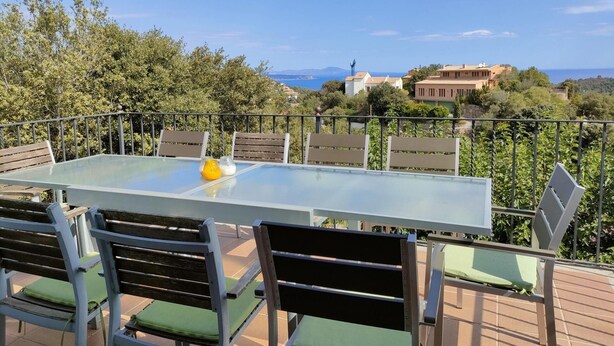 A terrace with a glass table and chairs, overlooking a scenic landscape with buildings and trees. - Villa Rosa Casa Begur (Begur)