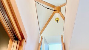 Een houten wenteltrap met een plafondventilator en dakraam.
