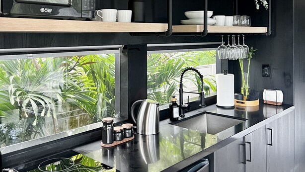 Una cocina moderna con microondas integrado, electrodomésticos de acero inoxidable y estantes de madera.