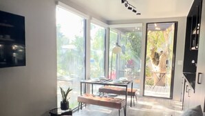 Un dormitorio moderno con una cama grande, una zona de comedor con mesa y sillas, y vistas al exterior a través de amplios ventanales.