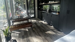 Una cocina moderna con armarios oscuros, una zona de comedor con banco, y un ventanal que proporciona luz natural.