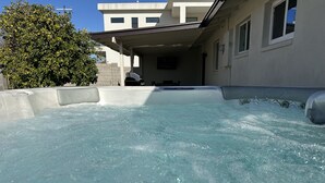 Un bain à remous offrant une vue dégagée sur les environs, notamment sur un bâtiment doté d’une terrasse couverte et sur un arbre.