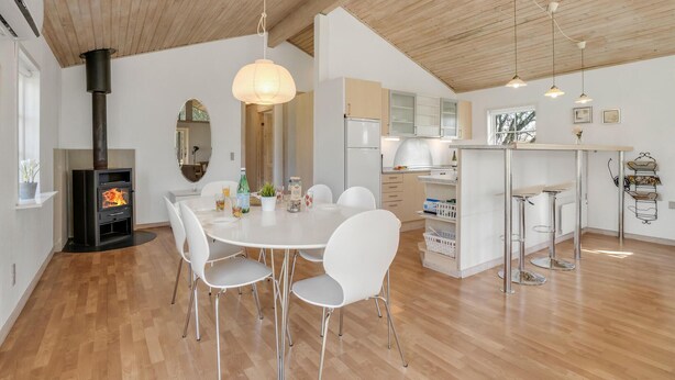 A modern kitchen with a central island, white chairs, and a dining table.