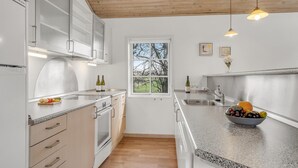 A modern kitchen with white cabinetry, a large window, and a granite countertop.
