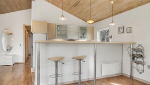 A modern kitchen with white cabinets, a central island, and two bar stools.