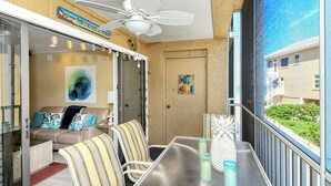 A balcony with a table, chairs, a ceiling fan, and a view of a building. - Direct beach access! Summer and fall dates still available, call today! (Bradenton Beach)