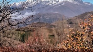 A mountain landscape with snow-capped peaks and a clear blue sky.