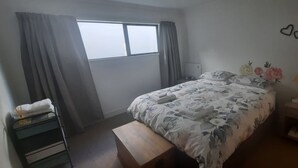 A bedroom with a bed, a bedside table, a lamp, and a window with curtains.