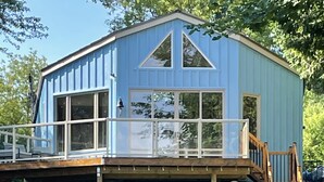 Ein blaues Haus mit Balkon, einer Holzterrasse und einer Leiter, die zum Obergeschoss führt.