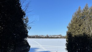 Schneebedeckte Landschaft mit blauem Himmel, einem eingezäunten Bereich und Bäumen.