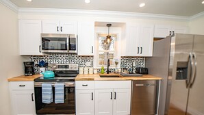 Een moderne keuken met witte kasten, roestvrijstalen apparatuur en een decoratieve spatwand.