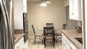 A compact kitchen with a dining table, chairs, a ceiling fan, and a refrigerator. - Relaxing 3 Bedroom, 2 Bathrooms. Large backyard, pool, jacuzzi + 2 patios, grill (Los Angeles)