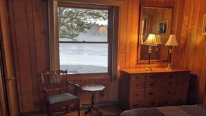 A cozy room with a wooden dresser, a chair, a small table, and a bed with a quilt.