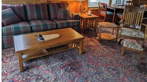 A cozy room with a plaid sofa, a wooden coffee table, and a patterned rug.