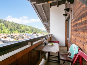 Un balcon avec une table, des verres à vin et une assiette de raisins.