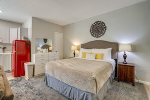 A bedroom with a bed, bedside tables, a nightstand, a dresser, a red refrigerator, and a mirror. - Experience Vegas in Style – Chic Private Suite Near the Strip (Las Vegas)