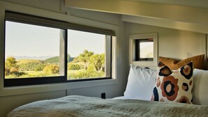 Un dormitorio con un amplio ventanal que ofrece vistas a un paisaje verde.