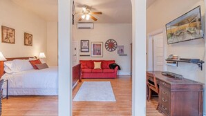 A room with a bed, a red sofa, a wooden desk, and a ceiling fan. - Rustic Studio walking distance to Downtown (Reno)
