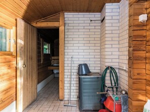 Interior de madera con pared de ladrillo, un lavamanos de metal y una puerta que da a otra habitación.