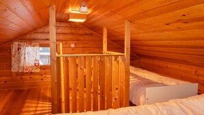 A cozy attic bedroom with wooden walls and a sloped ceiling. - Susitupa 6 by Interhome (Salla)