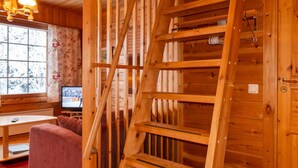 A wooden interior with a wooden ladder leaning against a wall, a sofa, and a television on a stand. - Susitupa 6 by Interhome (Salla)