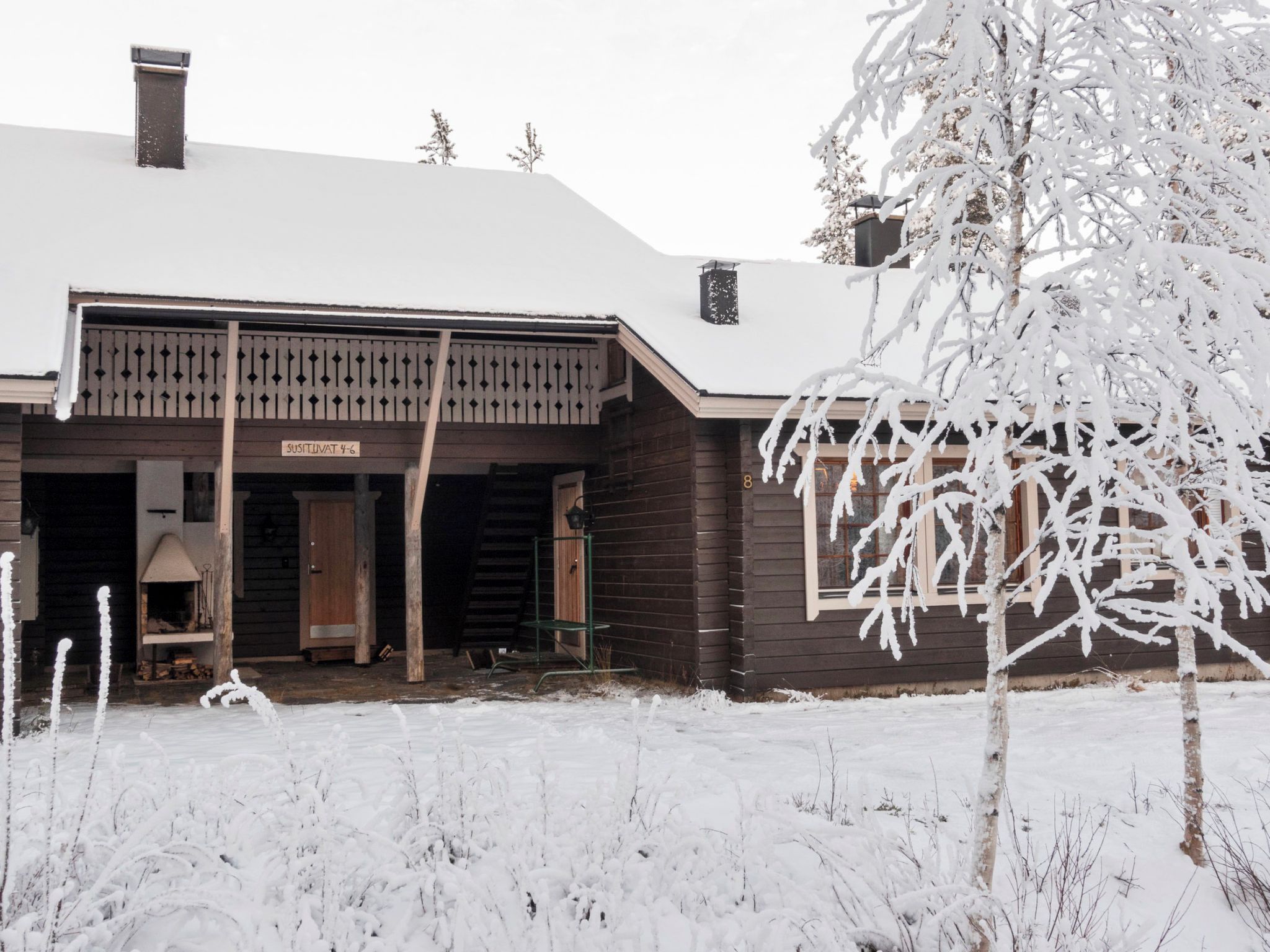 Une maison en bois avec un toit enneigé et une véranda.
